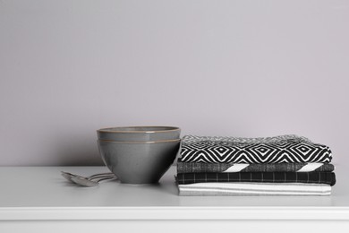 Photo of Kitchen towels and tableware on white countertop near wall