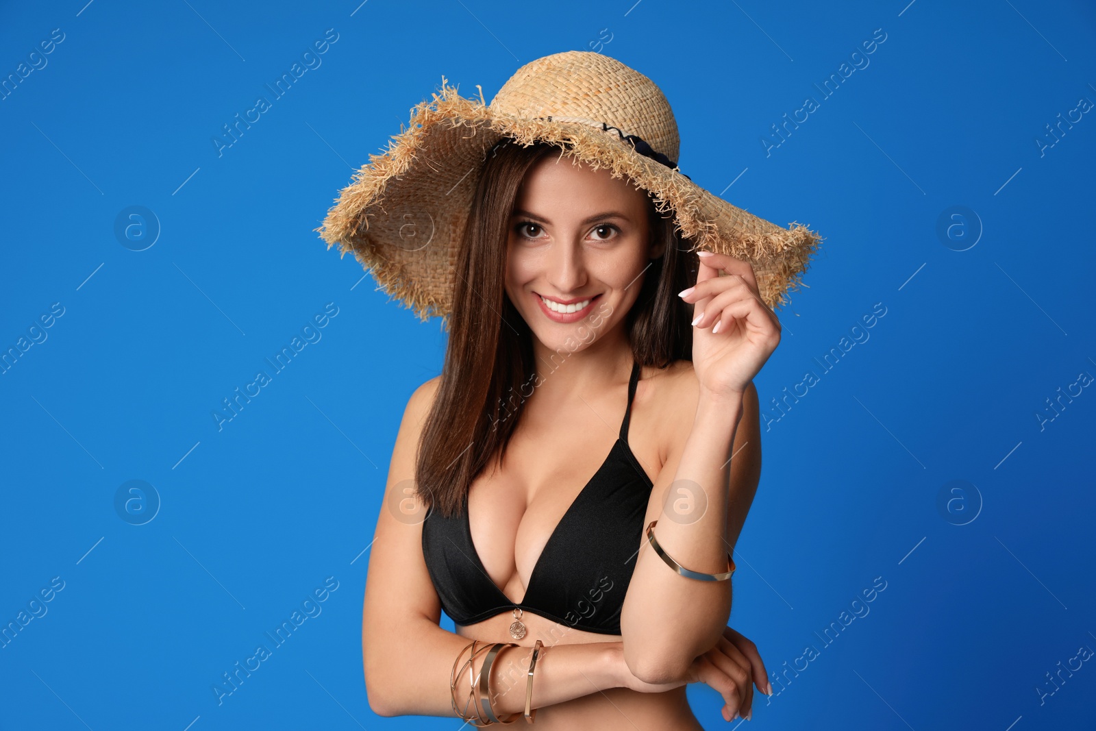 Photo of Pretty sexy woman with slim body in stylish  black bikini on blue background