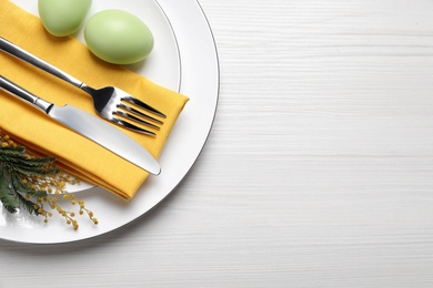 Festive Easter table setting with eggs on white wooden background, top view. Space for text