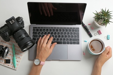 Photo of Female photographer using laptop at table, top view