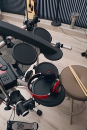 Photo of Modern electronic drum kit with headphones indoors, closeup. Musical instrument