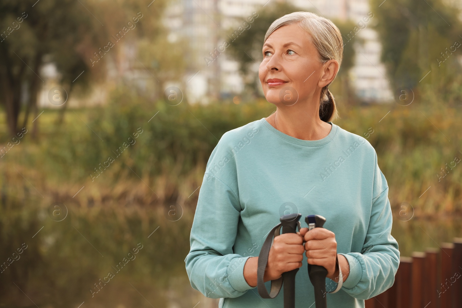 Photo of Senior woman with Nordic walking poles outdoors, space for text