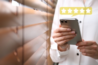 Woman leaving review online via smartphone indoors, closeup. Five stars over gadget