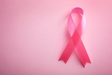 Photo of Pink ribbon on color background, top view with space for text. Breast cancer awareness concept