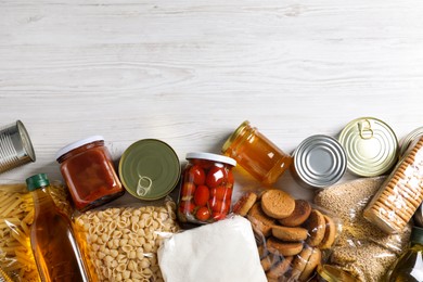 Photo of Different products on white wooden table, flat lay with space for text. Food donation