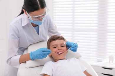 Dentist examining little boy's teeth in modern clinic