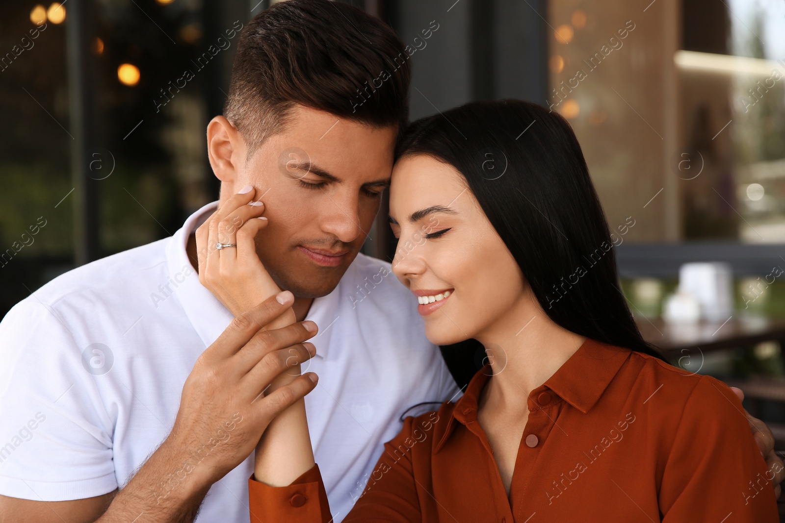 Photo of Lovely couple with beautiful ring after engagement in outdoor cafe