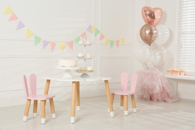 Photo of Small table with treats in room decorated for birthday party