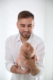 Father with his newborn son on light background