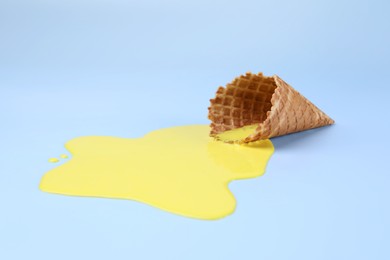 Photo of Melted ice cream and wafer cone on light blue background
