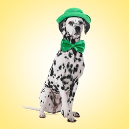 St. Patrick's day celebration. Cute Dalmatian dog with leprechaun hat and green bow tie on yellow background