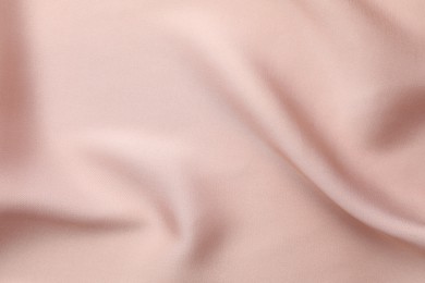 Crumpled pink silk fabric as background, top view