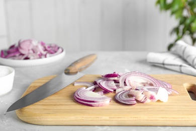 Photo of Wooden board with cut fresh red onion and knife on table