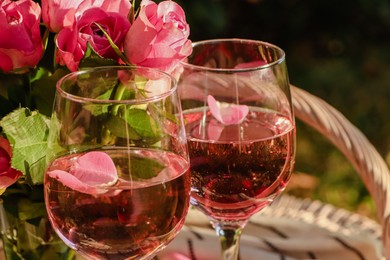 Photo of Glassesdelicious rose wine with petals and flowers outside, closeup