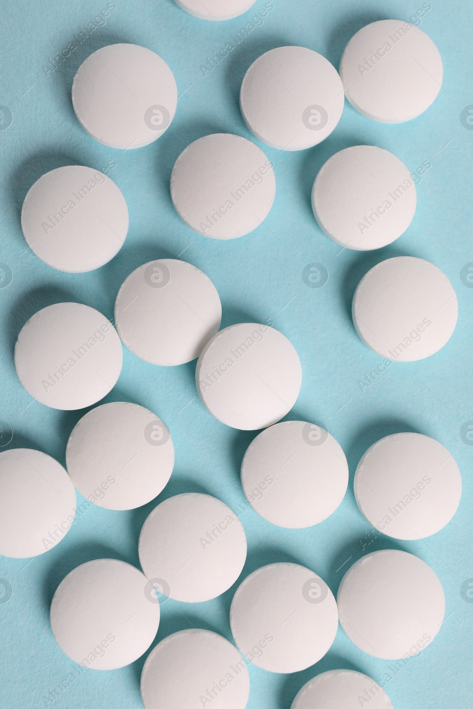 Photo of Many white pills on light blue background, flat lay