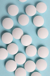 Photo of Many white pills on light blue background, flat lay