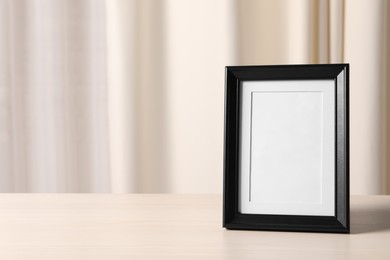 Photo of Empty square frame on white wooden table indoors, space for text