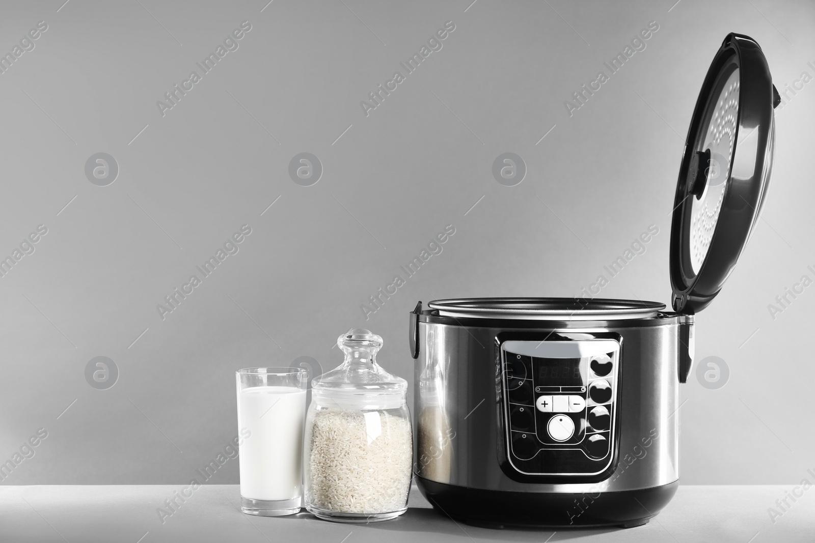 Photo of Modern powerful multi cooker and products on table against grey background. Space for text