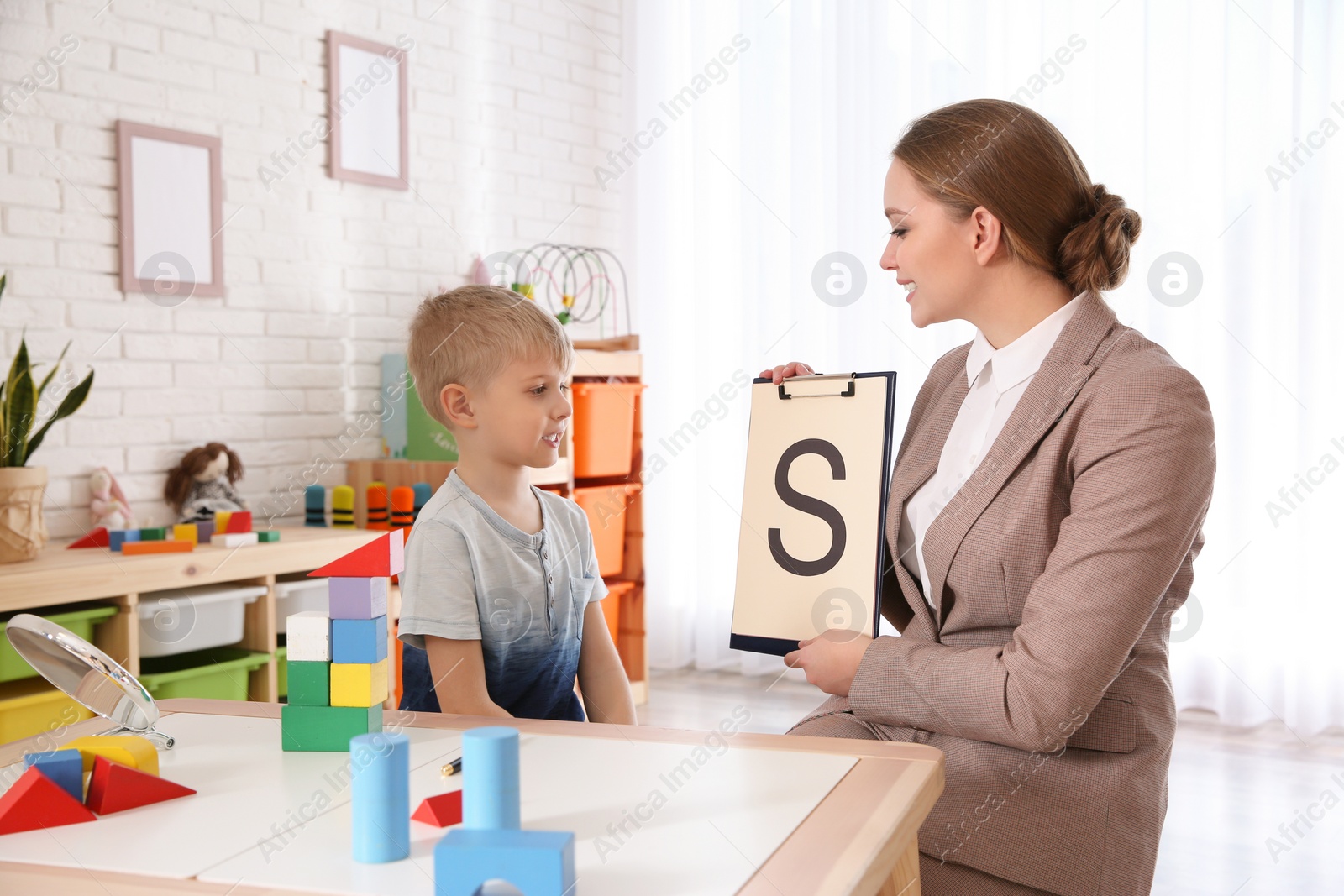 Photo of Speech therapist working with little boy in office