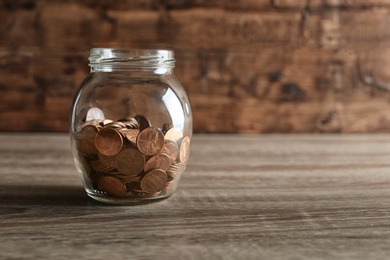 Donation jar with coins on table. Space for text