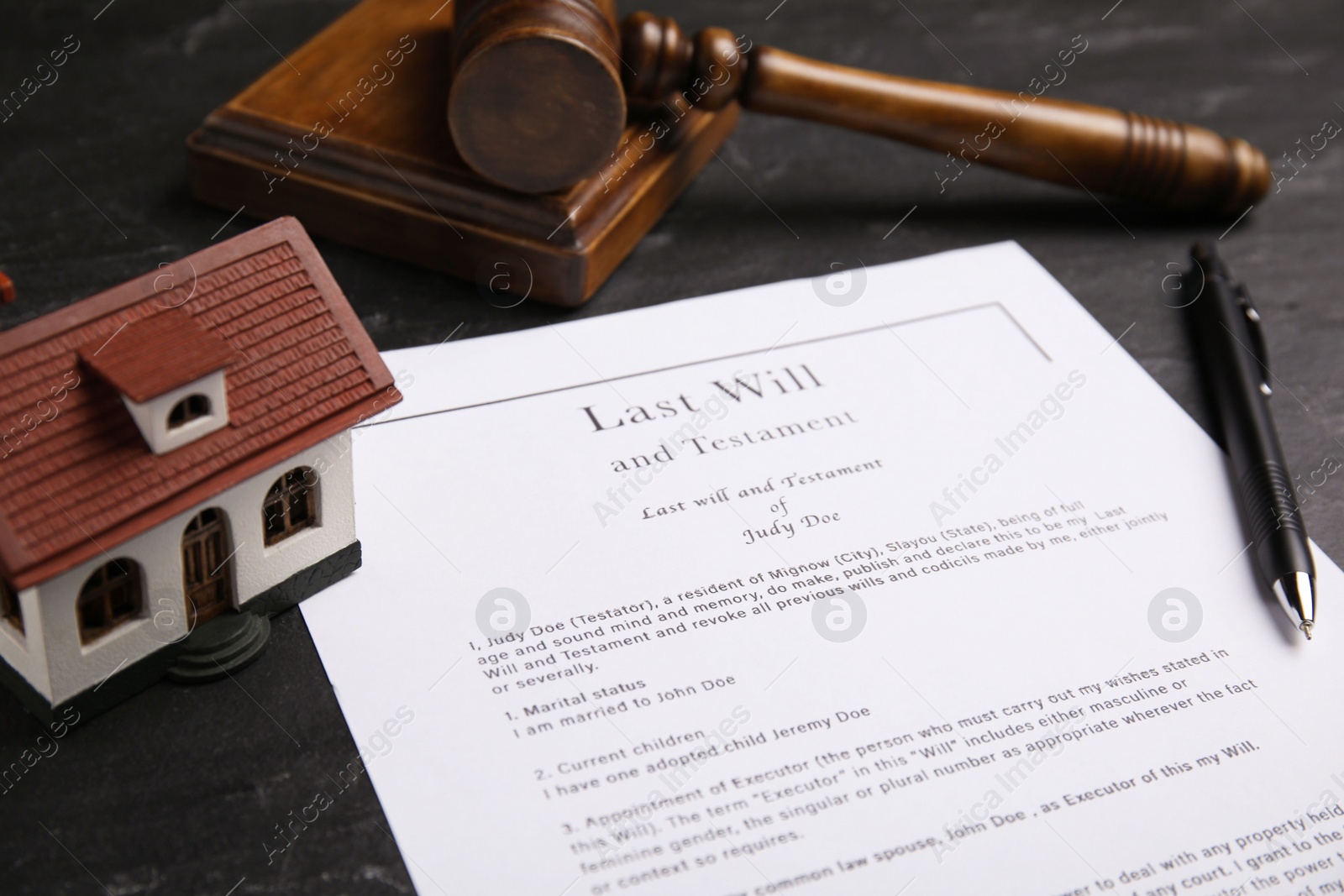 Photo of Last will and testament near house model, pen, gavel on black table, closeup