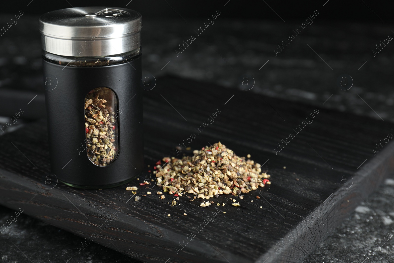 Photo of Stylish shaker with pepper on dark table, closeup
