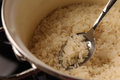 Pot with delicious rice and spoon, closeup