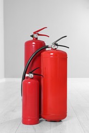 Photo of Three red fire extinguishers on floor indoors