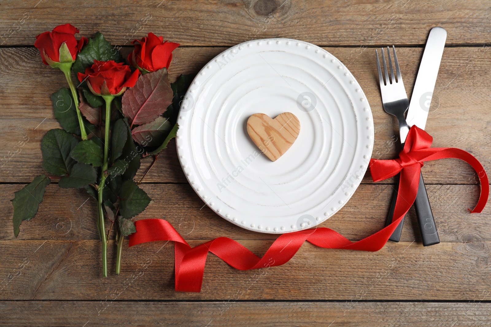 Photo of Beautiful place setting for romantic dinner on wooden table, flat lay. Valentine's day celebration