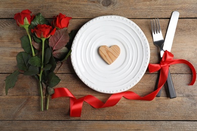 Photo of Beautiful place setting for romantic dinner on wooden table, flat lay. Valentine's day celebration