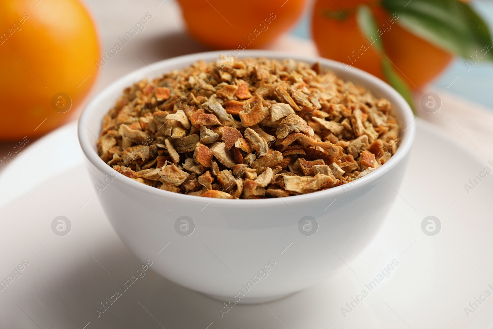 Photo of Bowl of dried orange zest seasoning and fresh fruits on plate