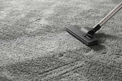 Photo of Removing dirt from grey carpet with vacuum cleaner. Space for text