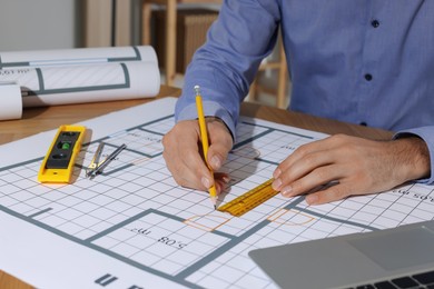 Photo of Architect working with construction drawings in office, closeup