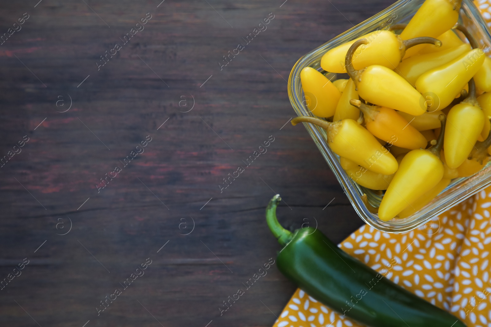 Photo of Fresh and pickled jalapeno peppers on wooden table, top view. Space for text