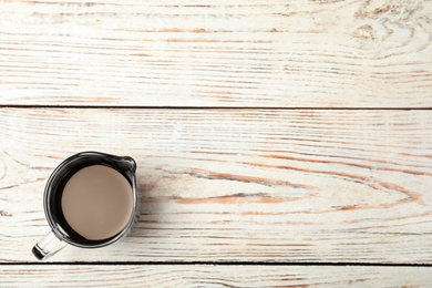 Photo of Jug with balsamic vinegar and space for text on wooden background, top view