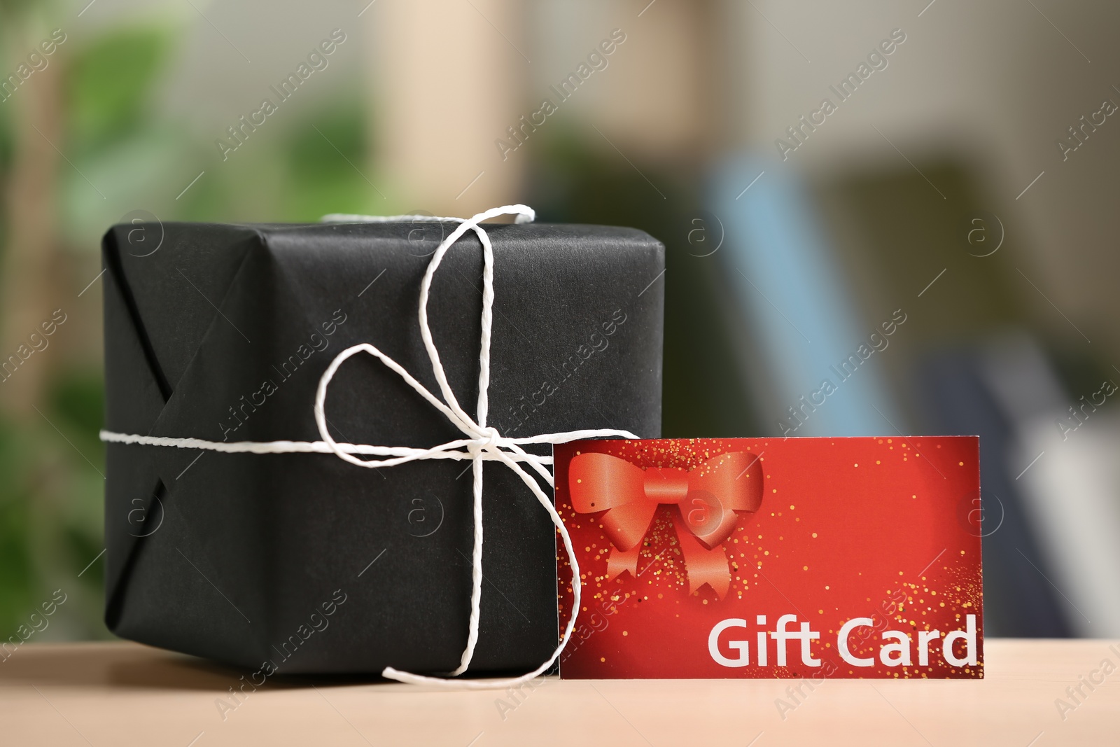 Photo of Gift card and present on table against blurred background