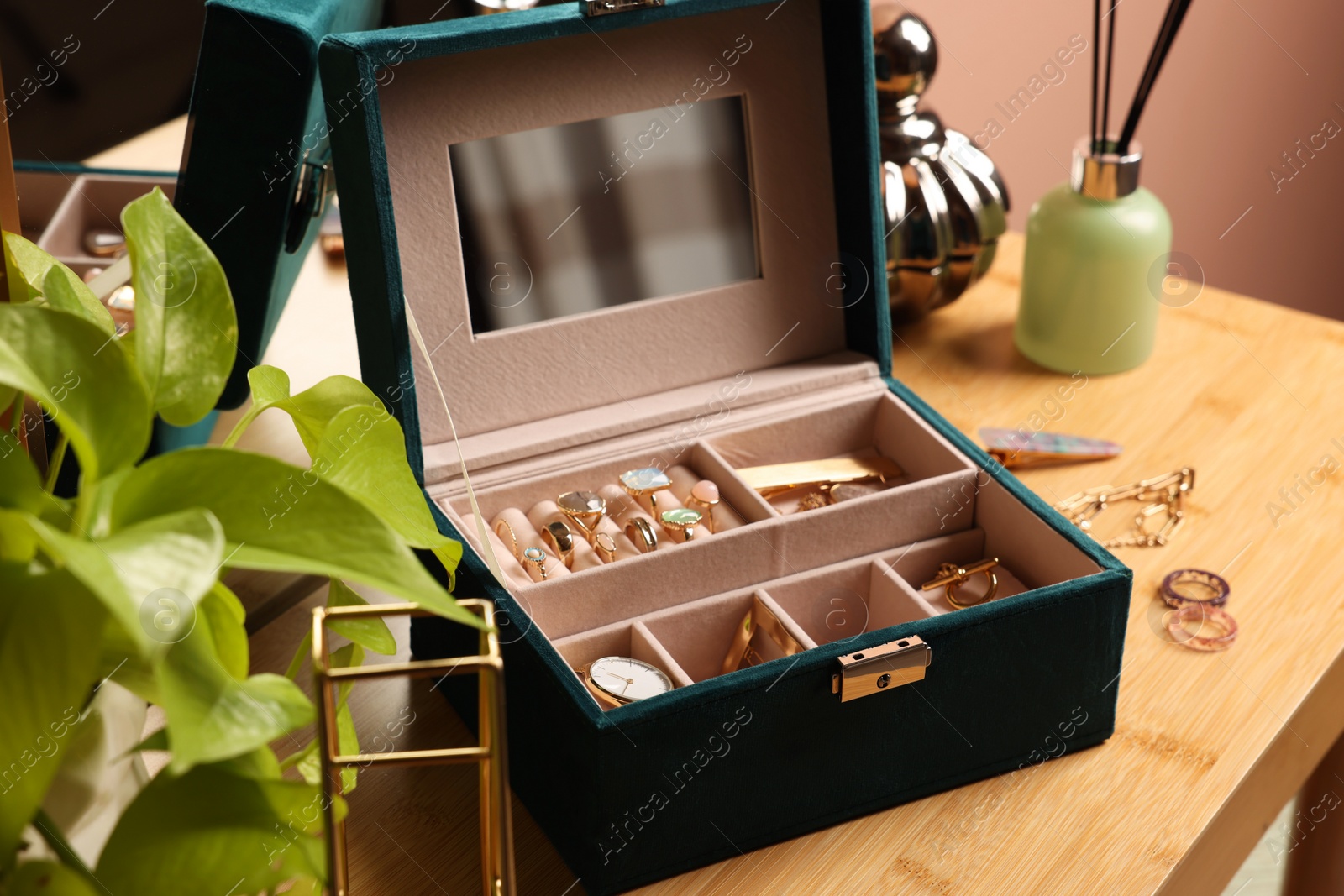 Photo of Elegant jewelry box with beautiful bijouterie and expensive wristwatch on wooden table