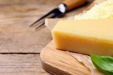 Photo of Delicious parmesan cheese and basil on wooden table, closeup. Space for text