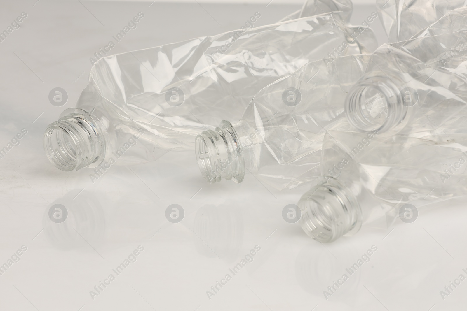 Photo of Crumpled disposable plastic bottles on white background