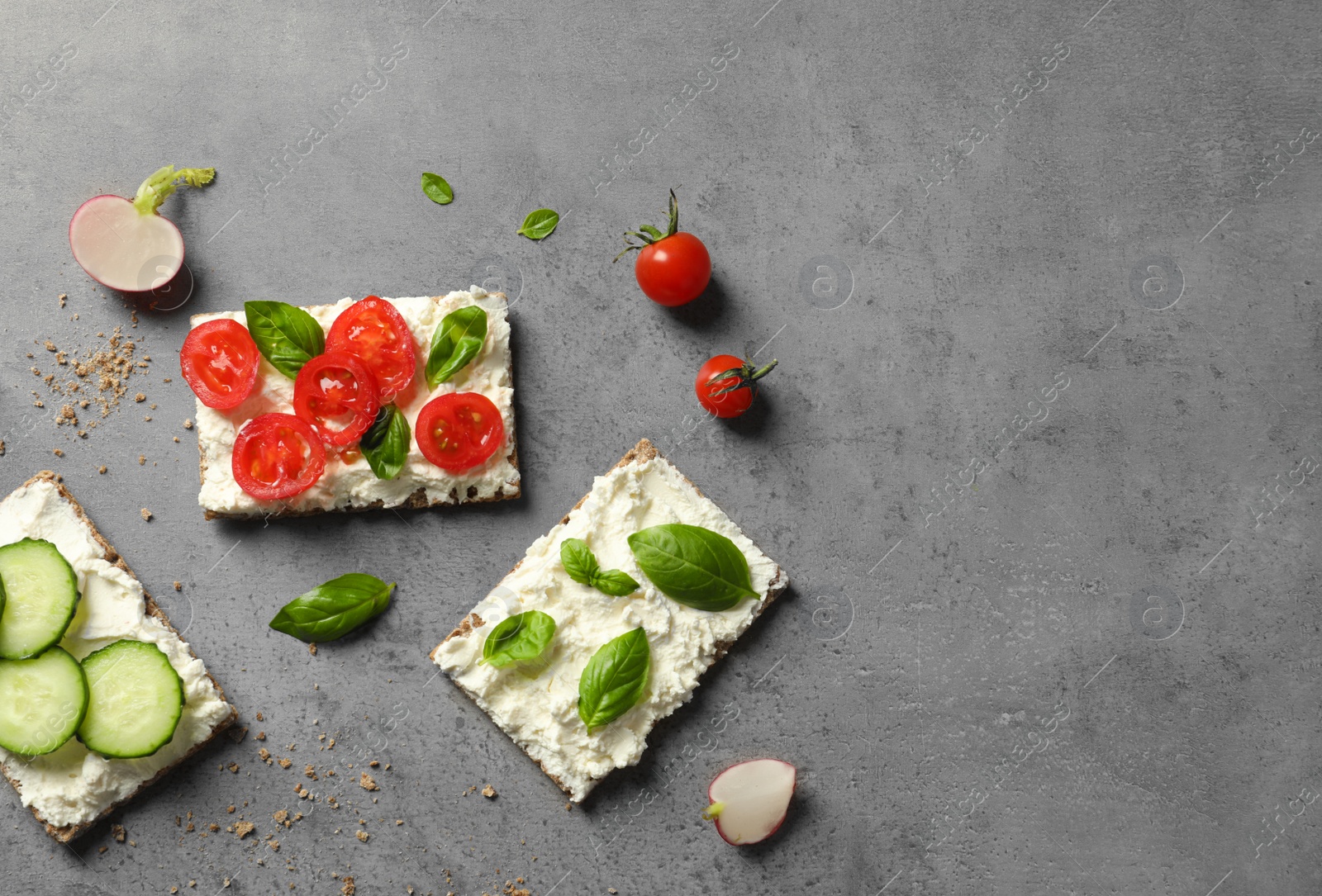 Photo of Tasty snacks with cream cheese and vegetables on gray table, flat lay. Space for text