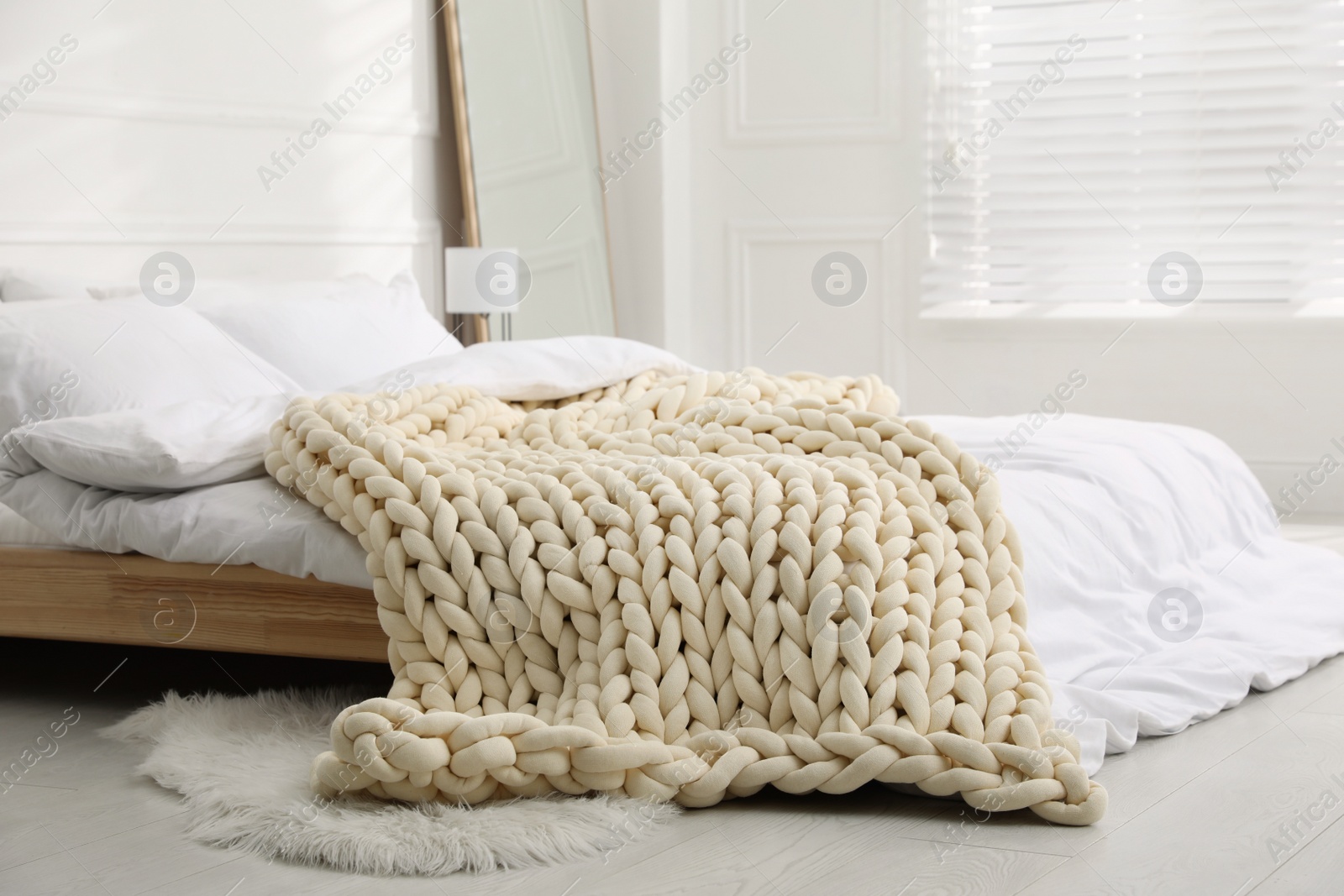 Photo of Soft chunky knit blanket on bed in stylish room interior