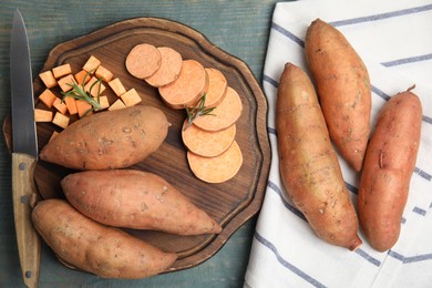 Photo of Sweet potatoes and knife on light blue wooden table, flat lay