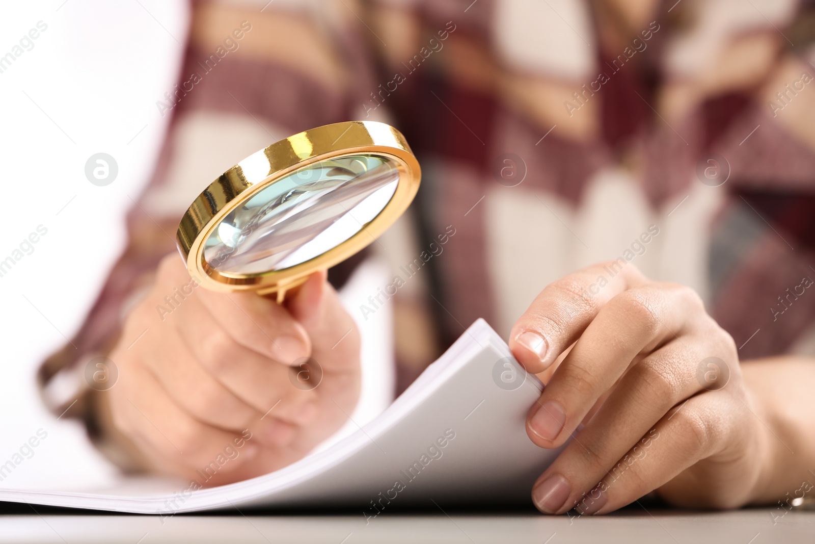 Photo of Woman using magnifying glass at table, closeup