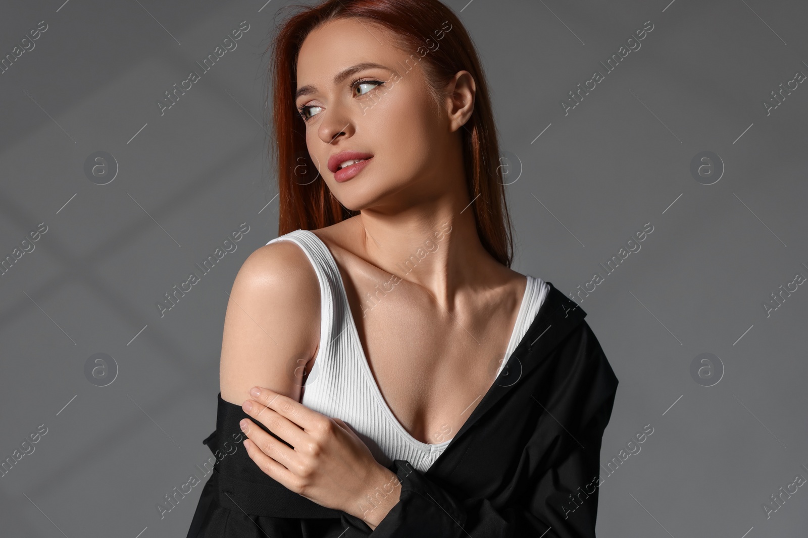 Photo of Beautiful young woman in black shirt on gray background