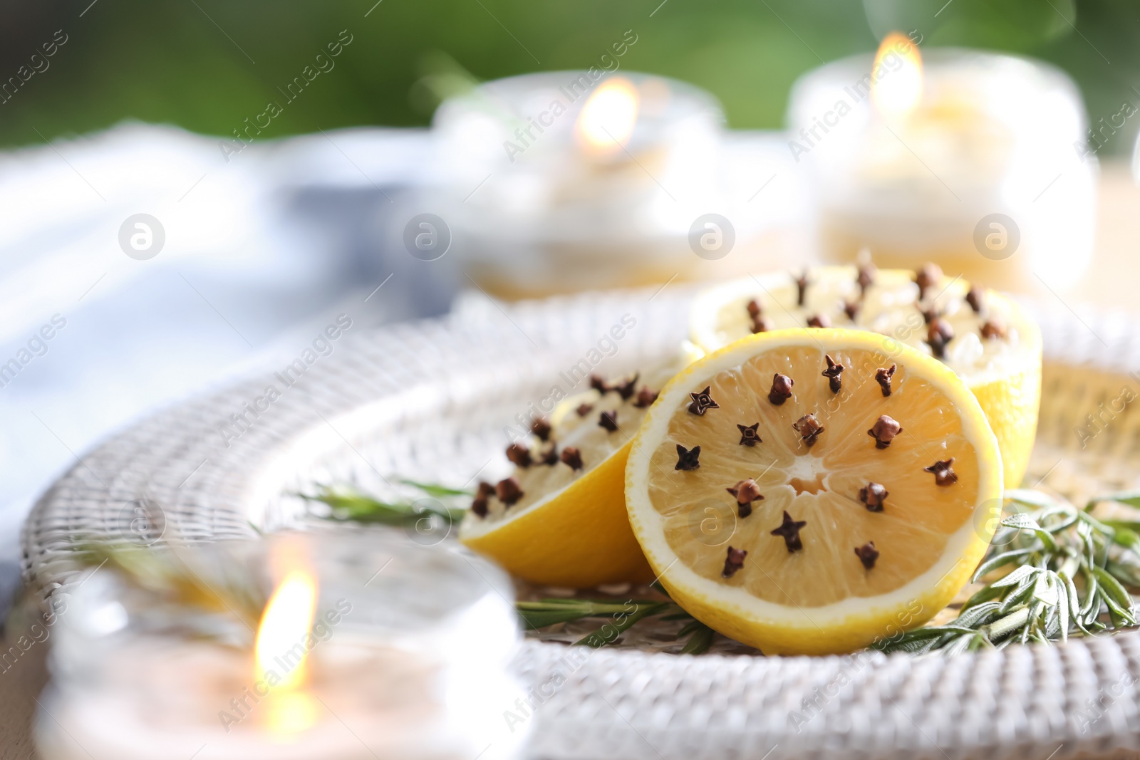 Photo of Lemons with cloves and fresh rosemary on plate outdoors, closeup. Natural homemade repellent