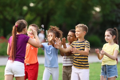 Photo of Cute little children playing with soap bubbles in park