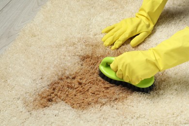 Photo of Woman removing stain from beige carpet, closeup