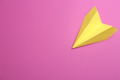 Photo of Yellow paper plane on purple background, top view. Space for text