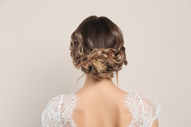 Young woman with beautiful hairstyle on beige background