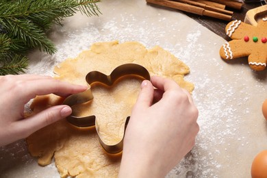 Photo of Woman making Christmas cookie with cutter at table, closeup